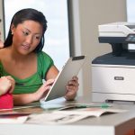 Twee vrouwen gebruiken een tablet voor een Xerox® VersaLink B415 multifunctionele printer