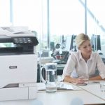 Twee vrouwen aan het werk in een kantoor naast een Xerox® VersaLink® C625 multifunctionele kleurenprinter