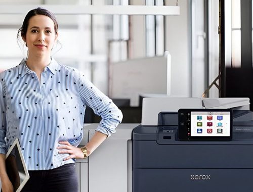 Een vrouw staat naast de Xerox® PrimeLink® C9200 Serie Printer in een moderne kantooromgeving