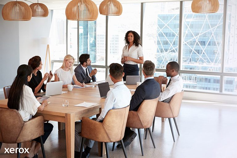 Een vrouw staat voor een groep, presenteert vol vertrouwen haar onderwerp en communiceert met het publiek tijdens de sessie.