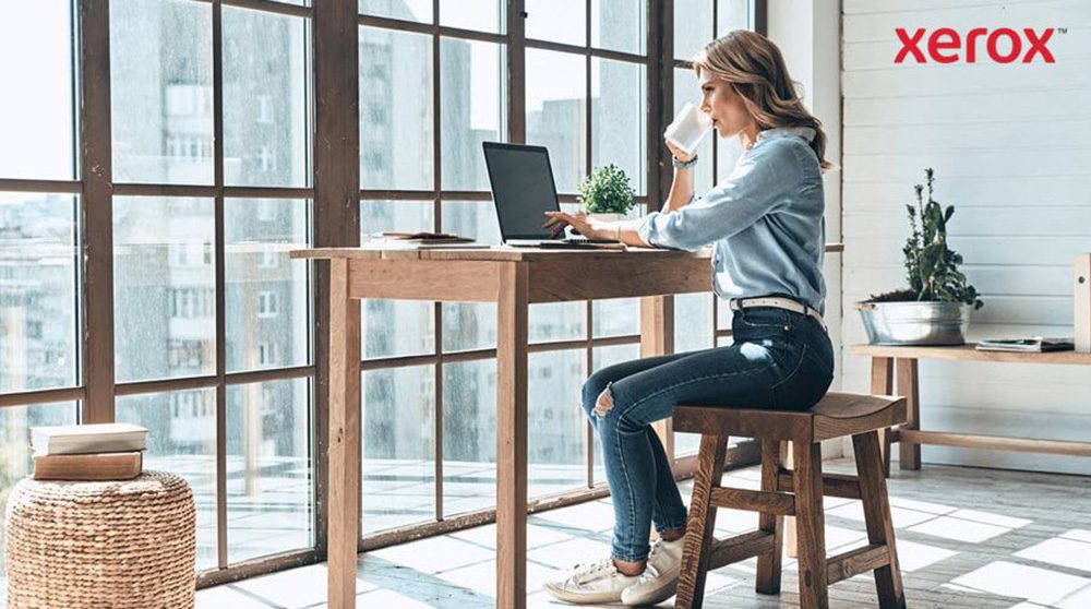 Une femme assise à un bureau, utilisant un ordinateur portable, faisant preuve de concentration et de productivité.